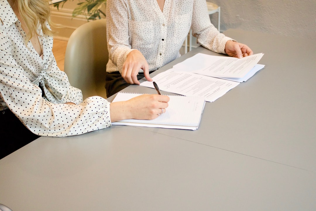 Two people reviewing and signing printed contract documents at a desk, illustrating the annual contracts behind annual recurring revenue